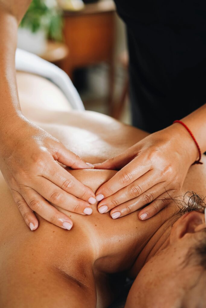 IMagine cu o Maseuză care efectuează un masaj terapeutic pe spatele clienti care este o doamnă brunetă